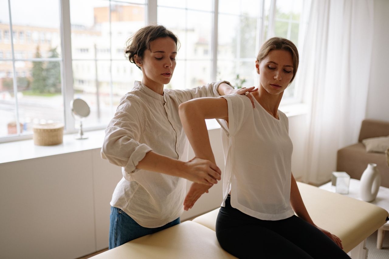 Home Therapist assisting woman in physical therapy session indoors with natural light.