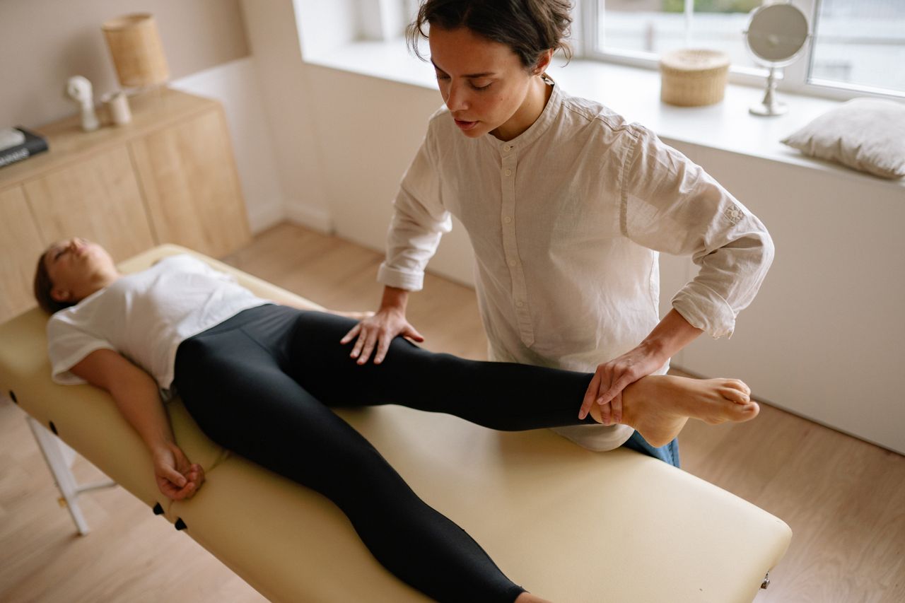 Home A physiotherapist assists a woman with leg rehabilitation therapy in a calm treatment room
